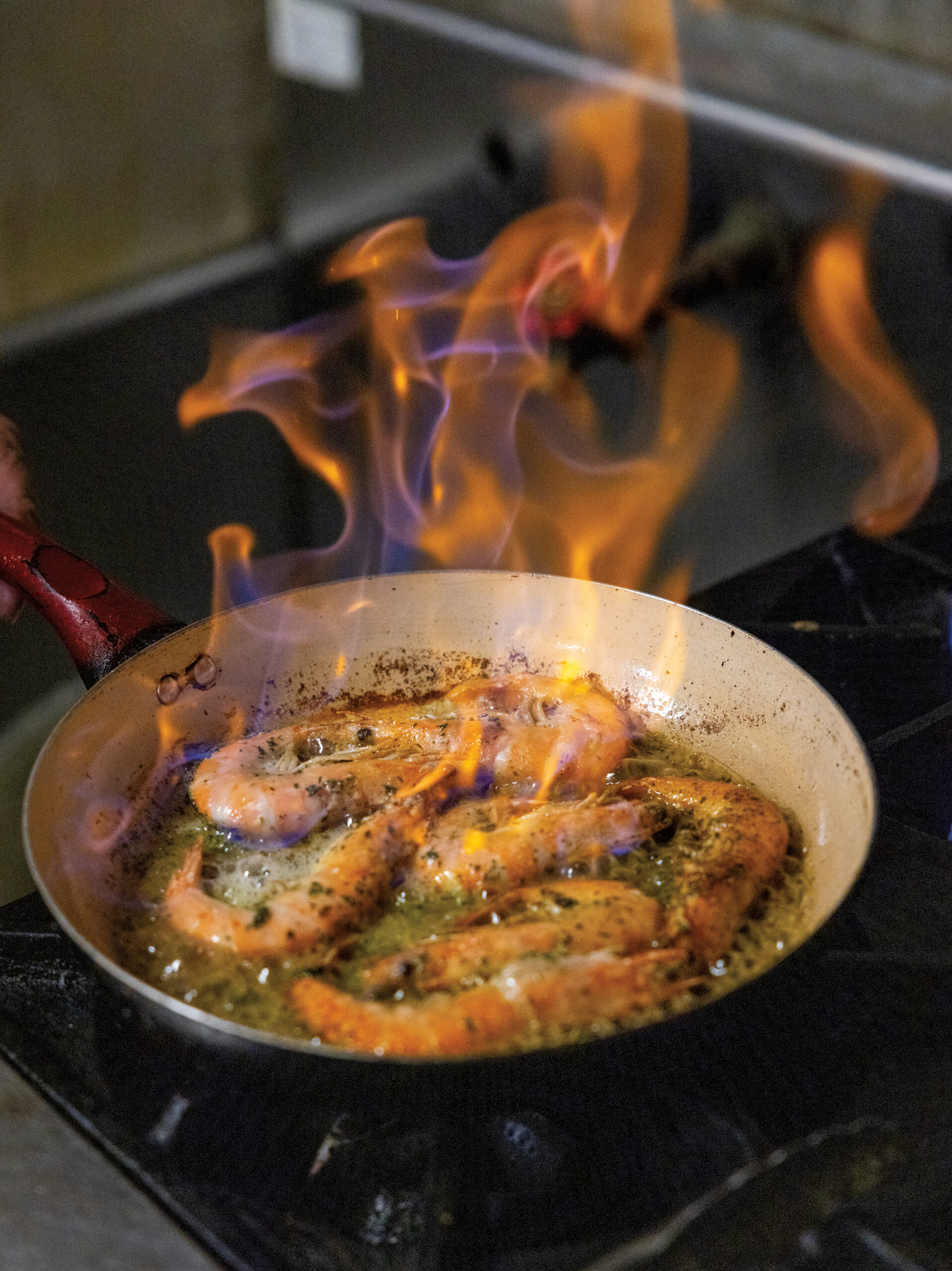 Experience French Cuisine with a Cajun Twist at Chez Jacqueline in Breaux Bridge - Louisiana Cookin' Text: Beth D'addano Photos: Kyle Carpenter Some Francophiles prefer white-tablecloth, fancy palaces of Gallic flavor—think Julia Child’s favorite, Chez Georges, a Parisian institution since 1926. Then there are the more casual family-style bistros that dish French fare in a relaxed setting. Chez Jacqueline is in that last number. To a first-timer, the restaurant is a Chez Jacqueline’s skillet with flames