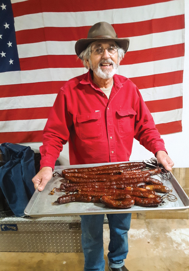 From Shreveport to Breaux Bridge: One Man’s Quest for the Perfect Boudin - Louisiana Cookin' Story and photography by Chris Jay My father, Donny, is a retired pipeline welder from Taylor, Arkansas, who moves and speaks so lethargically that his friends have dubbed him “Turtle.” In his retirement years, Turtle has developed an all-consuming interest in sausage-making, a topic that he will discuss in depth and at length with little Man holding sausage in front of american flag