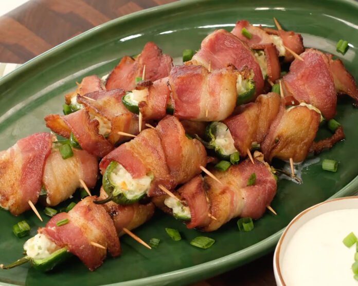 poppers-2 Bacon-wrapped jalapeño poppers filled with cream cheese, skewered on a green plate.