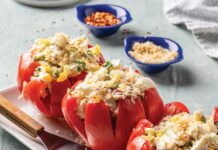 Crab-Stuffed Tomatoes Three hollowed red tomatoes filled with crab salad, egg, and herbs on a white platter, with lemon and chives nearby