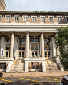 Worth the Drive: Small Towns with Big Charm - Louisiana Cookin'  Facade of a neoclassical brick building with tall columns and a wide set of stairs leading to double doors on a sunny street.