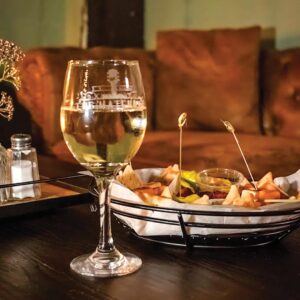 Weekend Away: Clarksdale, Mississippi - Louisiana Cookin' Set your sights on the Mississippi Delta for a soulful few days. Wine glass with white wine on a dark table beside a basket of chips and dip in a cozy restaurant setting.