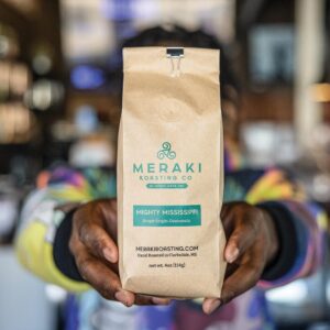 Weekend Away: Clarksdale, Mississippi - Louisiana Cookin' Set your sights on the Mississippi Delta for a soulful few days. Brown paper coffee bag labeled Meraki Roasting Co, Mighty Mississippi (Guatemala), being handed forward by hands in a colorful jacket.