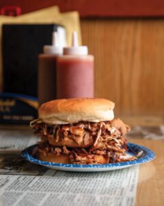 Weekend Away: Clarksdale, Mississippi - Louisiana Cookin' Set your sights on the Mississippi Delta for a soulful few days. Pulled pork sandwich piled high with sauce on a soft bun, served on a blue plate over a newspaper.