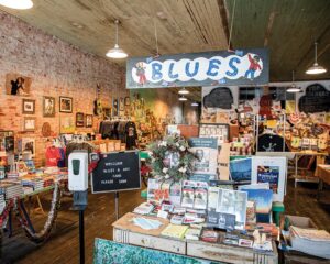 Weekend Away: Clarksdale, Mississippi - Louisiana Cookin' Set your sights on the Mississippi Delta for a soulful few days. Indie blues and arts shop interior with brick walls, a hanging 'BLUES' sign, and tables of books and posters.