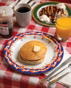 Weekend Away: Clarksdale, Mississippi - Louisiana Cookin' Set your sights on the Mississippi Delta for a soulful few days. Stack of pancakes with a pat of butter on a decorative plate, with coffee, orange juice, and syrup on a red checkered tablecloth.