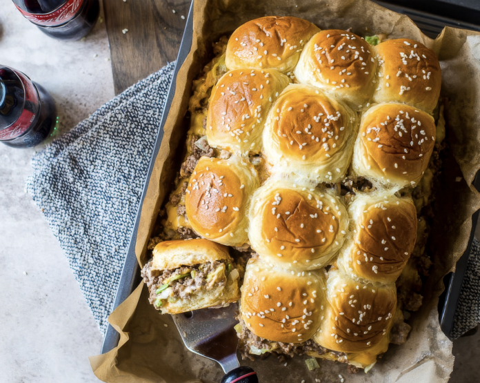 Savory beef sliders baked as a pull-apart monkey bread with sesame seeds in a parchment-lined pan, ready to serve.