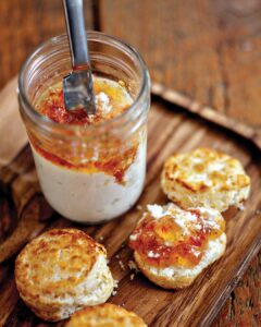 Bayou-Bakery_Biscuits_Scott-Suchman - Louisiana Cookin' Making Waves: Louisiana’s Own Culinary Trailblazers - Louisiana Cookin' Louisiana-born chefs making their mark across the South. Creamy dip in a glass jar with a metal spreader, surrounded by toasted bread rounds on a wooden board.