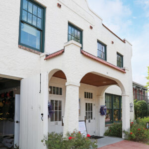 Fairhope-Museum-of-History_6819 - Louisiana Cookin' Weekend Away: Press Pause in Fairhope, Alabama - Louisiana Cookin' A gentle weekend escape to a city full of coastal charm. White stucco two-story building with arched entrance, green-framed windows, and red-tiled roof; flowers and wreaths decorate the doorway.