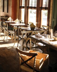 IMG_6790 - Louisiana Cookin' Making Waves: Louisiana’s Own Culinary Trailblazers - Louisiana Cookin' Louisiana-born chefs making their mark across the South. Sunlit cafe interior with wooden tables, white chairs, and warm window light from large blinds.