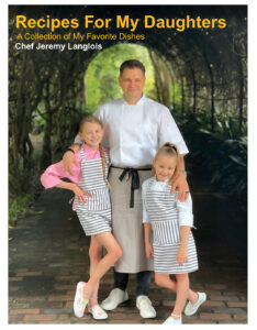 RecipesForMyDaughtersCover - Louisiana Cookin' Putting His Heart on the Plate: Inside Chef Jeremy Langlois’ Culinary Journey - Louisiana Cookin' Chef Jeremy Langlois reflects on his decades-long culinary journey—from training under legendary John Folse to Houma's House to his latest venture, a self-published cookbook. Cookbook cover: Chef Jeremy Langlois with two girls in striped aprons posing outdoors under a leafy arch, title 'Recipes For My Daughters'.