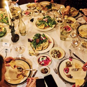 Magic on Lake Martin: Inside Louisiana’s Secret Supper Series - Louisiana Cookin' The guest list is small, the chefs are kept under wraps, and the meal is one to remember. Round dining table set for a meal with salads, bowls, candles, and wine glasses on a white tablecloth