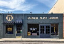 New + Interesting: July/August 2026 Storefront of Gravy Lafayette restaurant with a dark blue exterior and a sign reading 'ACADIANA PLATE LUNCHES' above the door and windows.
